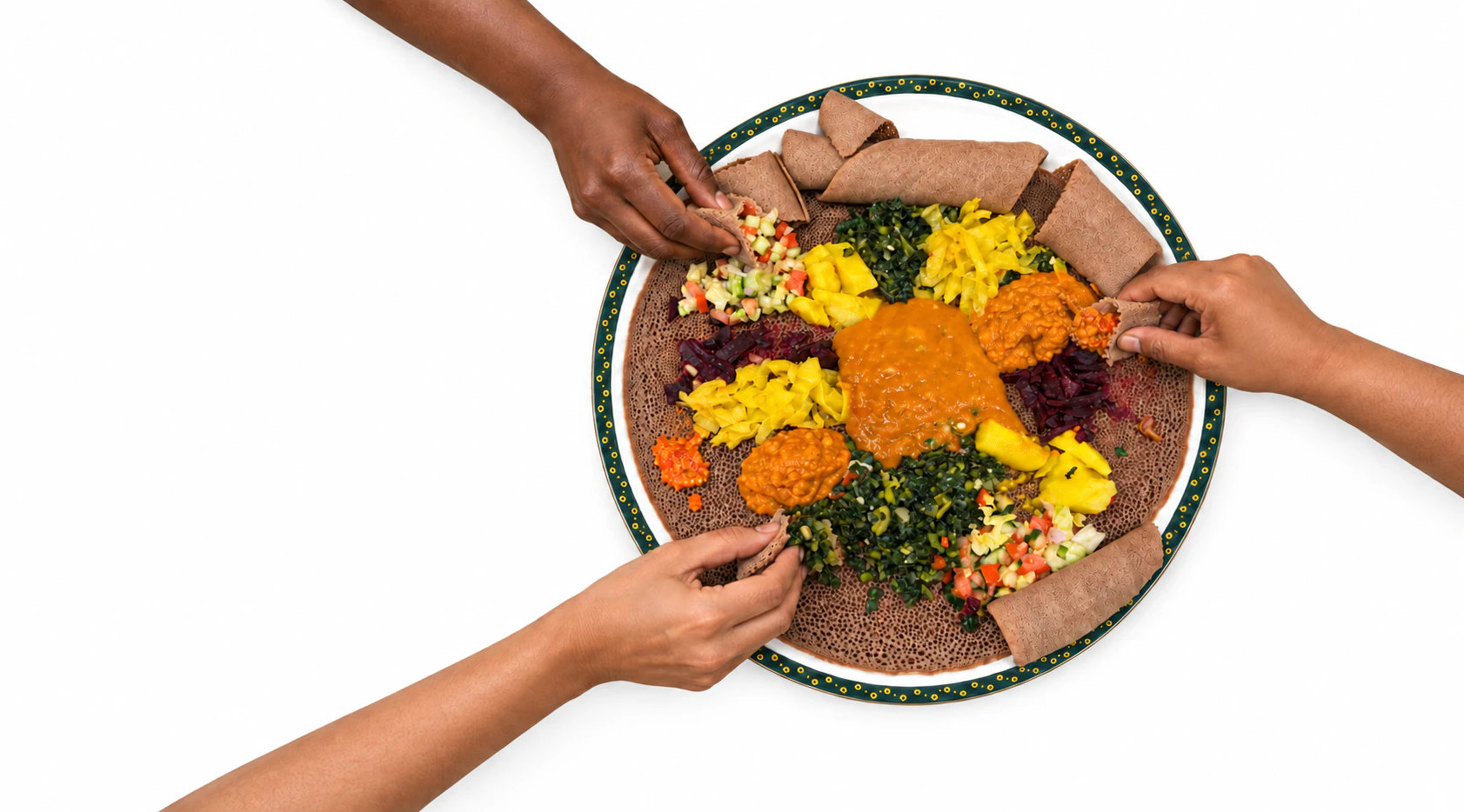 Three diners reach across the table with injera to share a vegetarian platter of stews, greens and vegetables